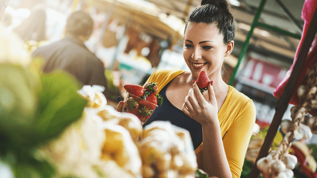 Young woman shopping for strawberries at a farmers market